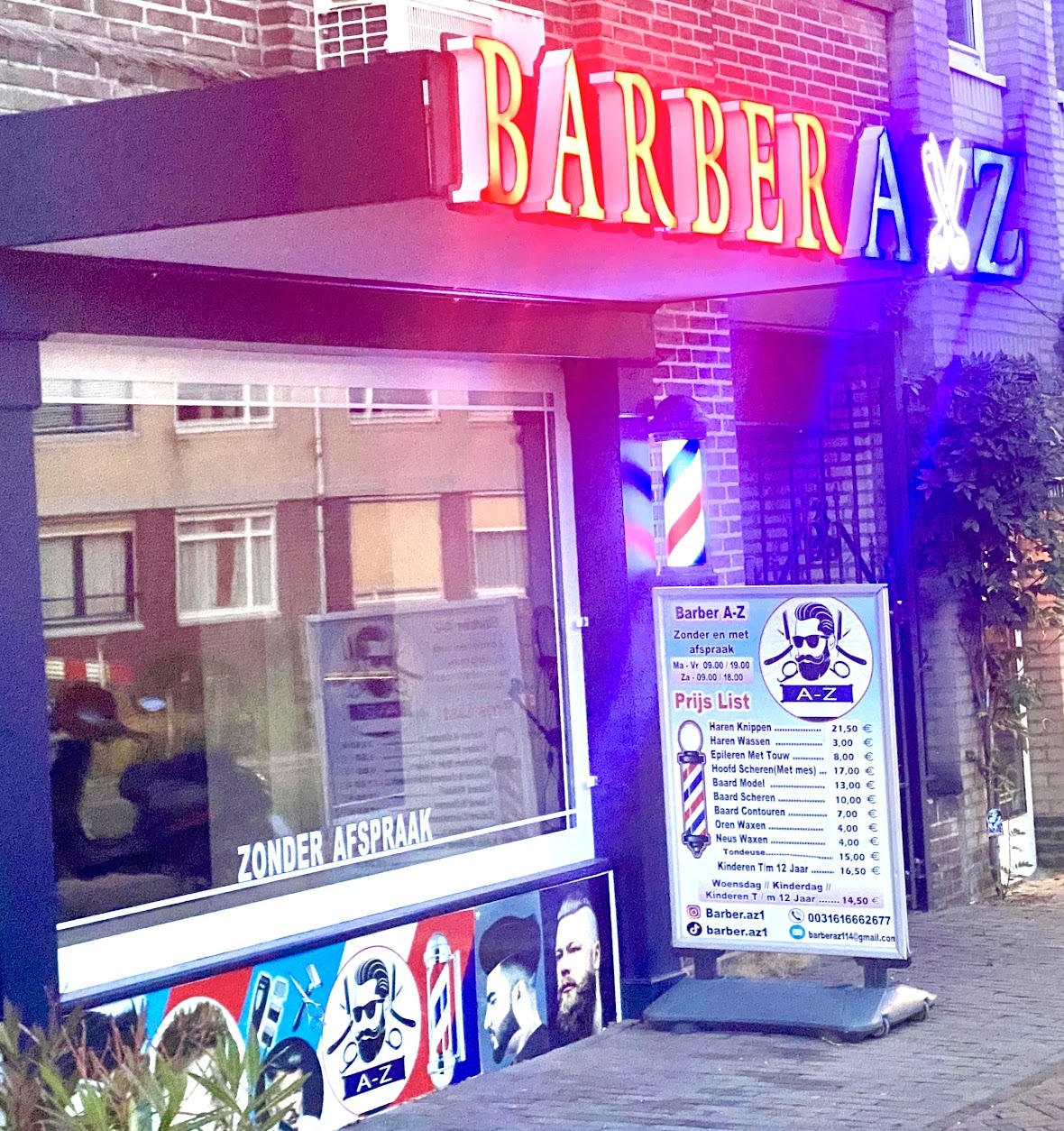 De gevel van Barber A-Z bij schemer, met de neonletters, de barberspaal en het bord met openingstijden